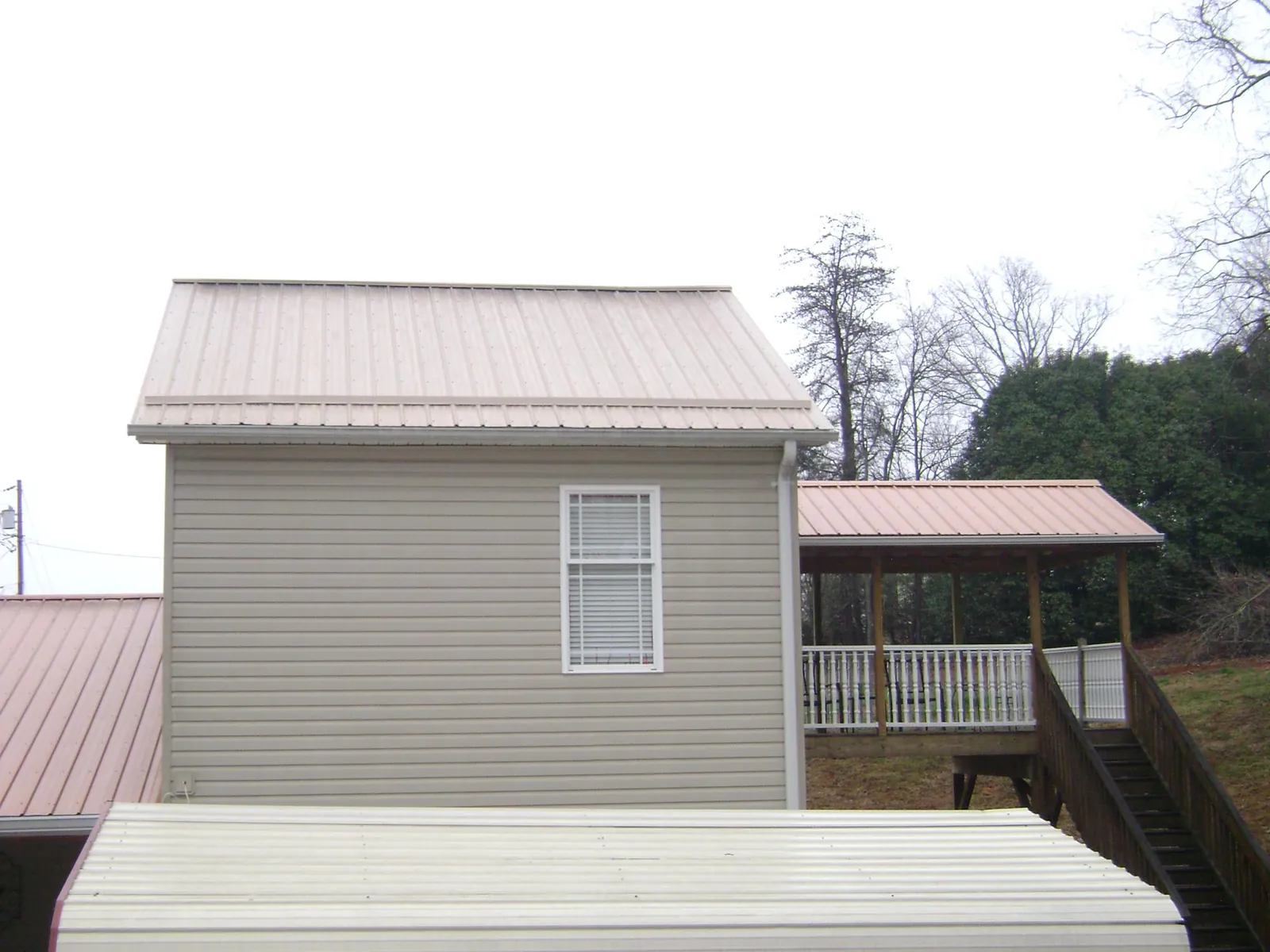 Tan metal roofs on a two story addition and attached porch, from a Roof Replacement job in Billings
