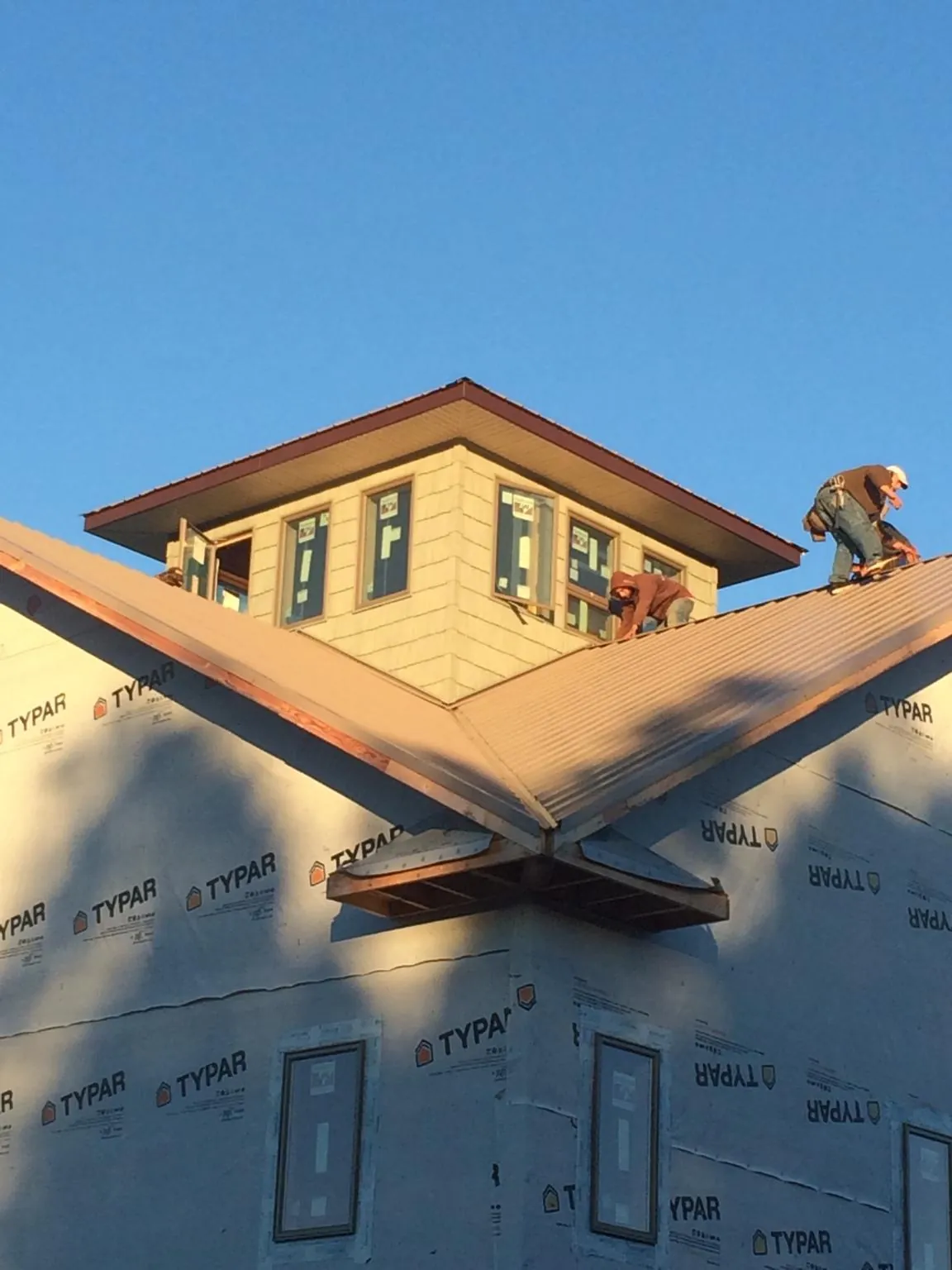 Roofers working around a rooftop cupola on a new metal roof at sunset — Roof Waterproofing in Billings by Roofing Brothers